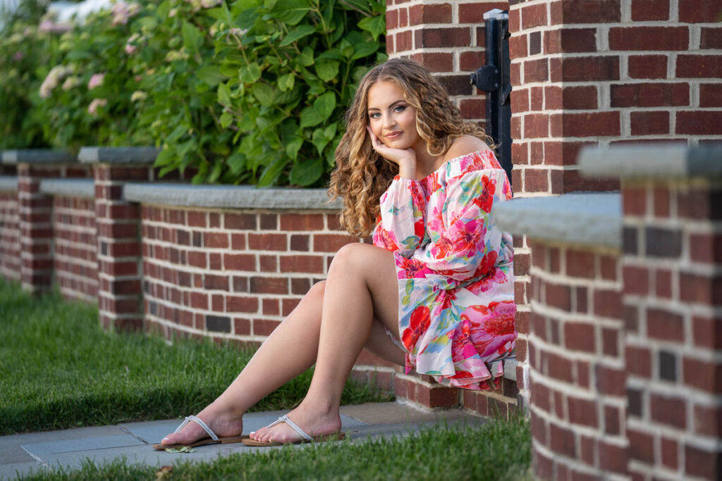 beautiful senior sitting during a senior photo session by a brick wall in Ocean City Nj