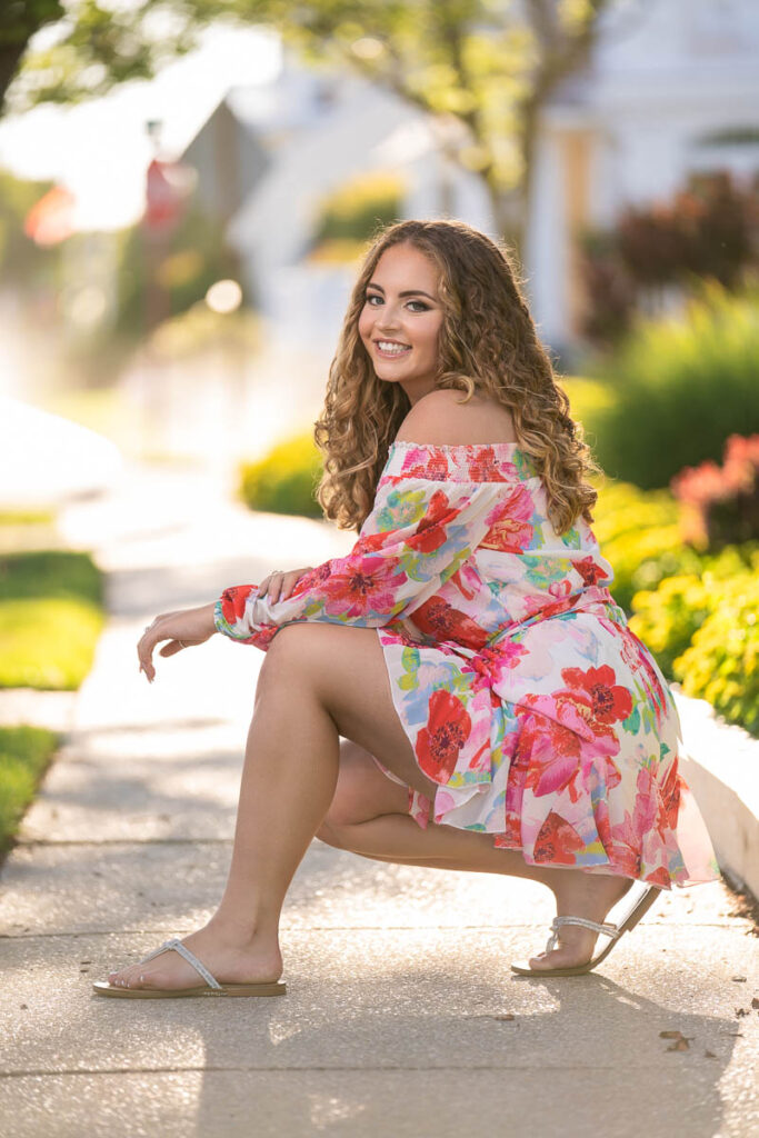 senior smiling wearing a floral romper during photo session on the streets of Ocean City NJ