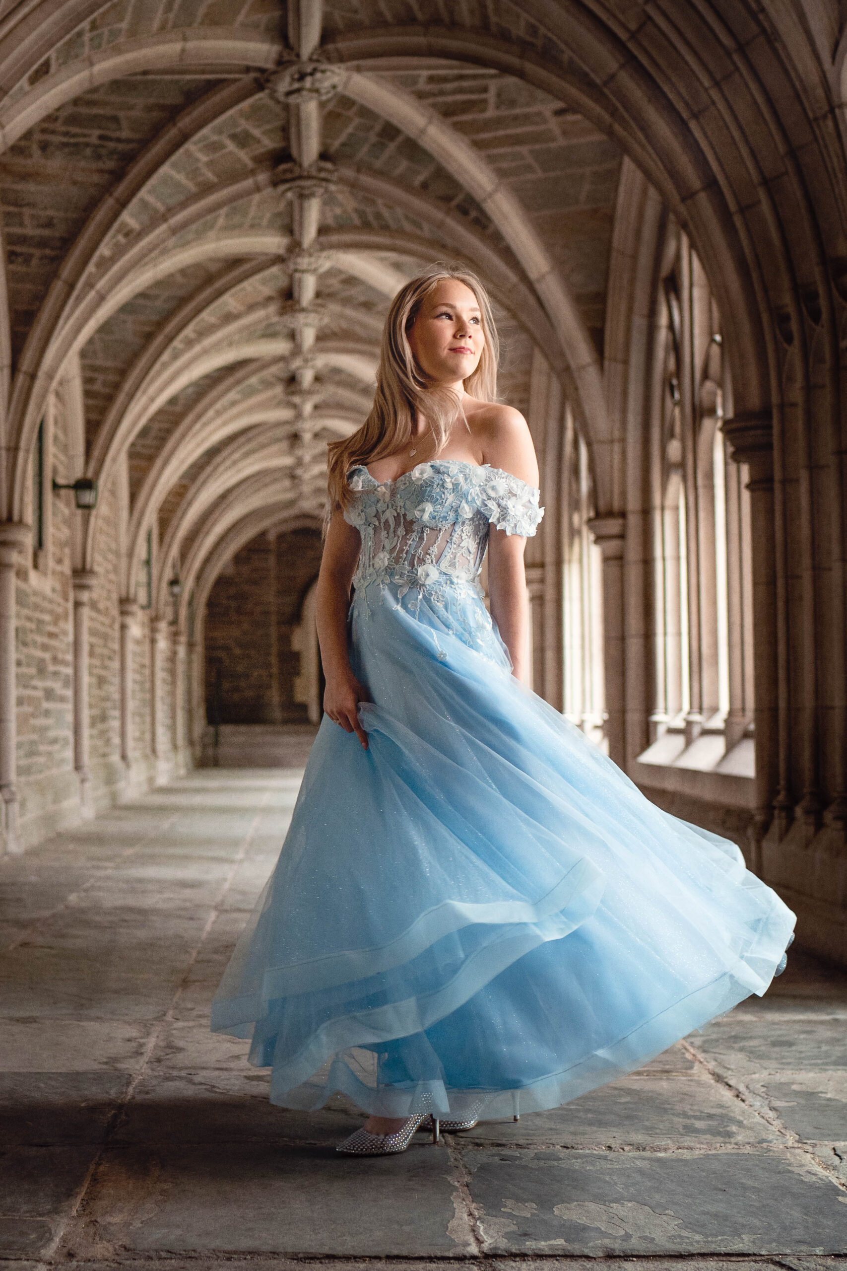beautiful blonde high school senior wearing a light blue fairytale gown in a castle like setting